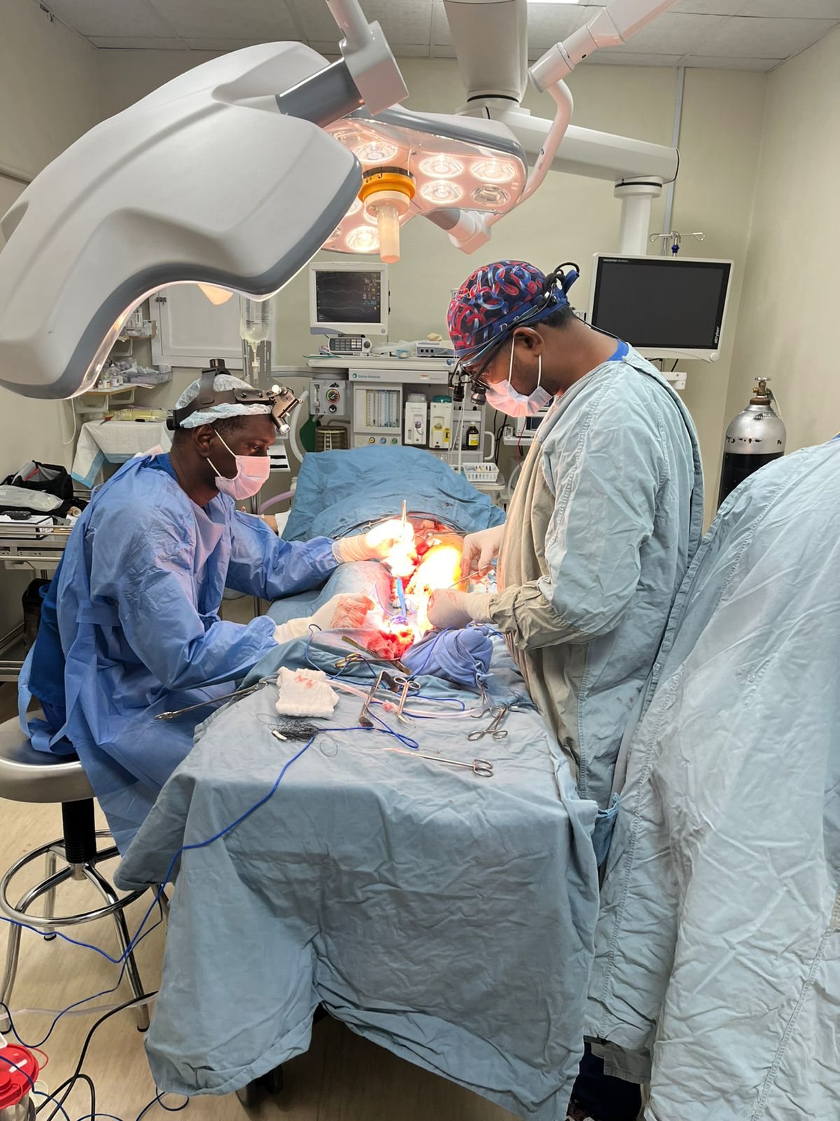 Surgeons operating under theatre lights during a lower limb arterial bypass at Newtown Medical Centre
